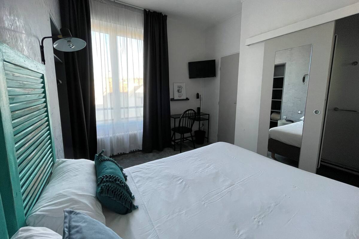 Ett hotellrum med en säng, ett skrivbord, en stol, en tv och en garderob.