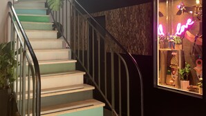 A staircase with a metal railing, wooden steps, and a neon sign on the right. - Urban Jungle. Hotel Orléans (Orléans)