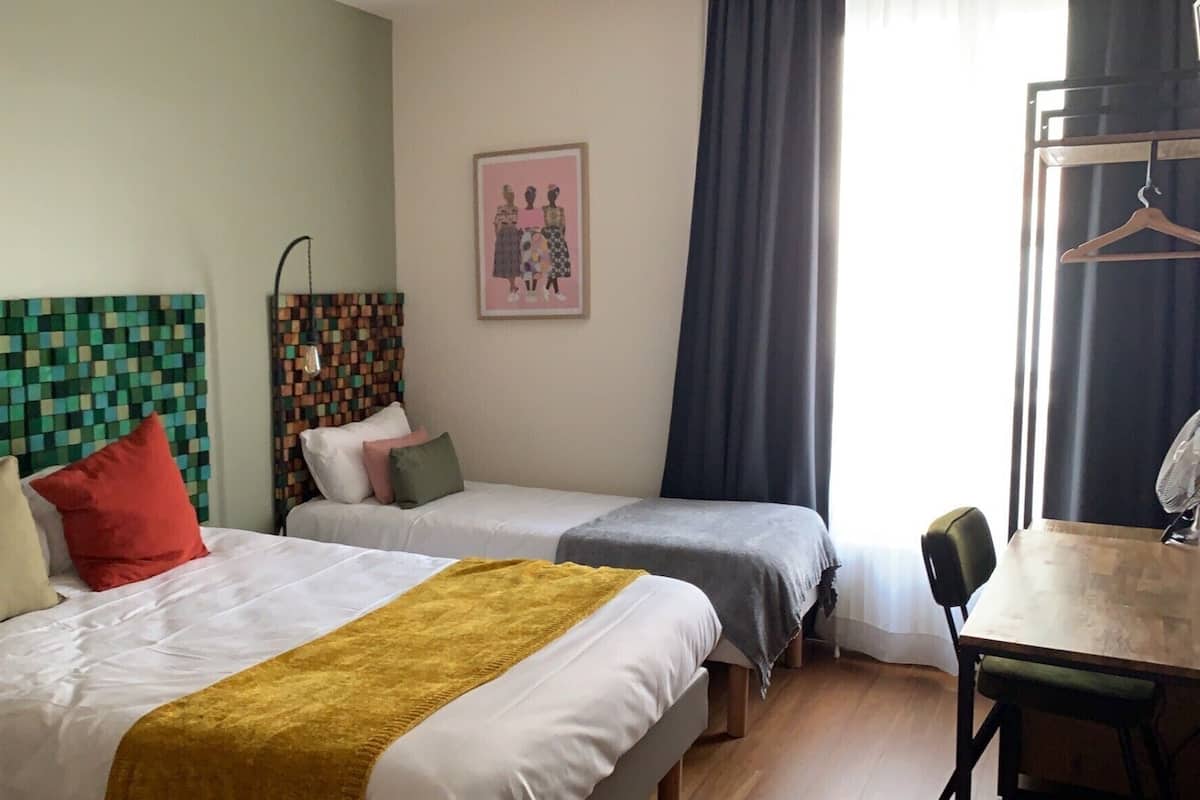 Ett hotellrum med två sängar, ett skrivbord och en stol.