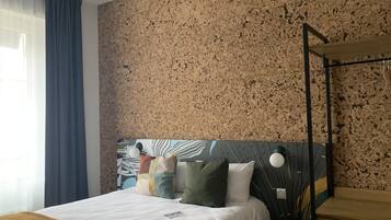 A modern bedroom with a bed, a wooden nightstand, a wall-mounted desk, and a ceiling fan.