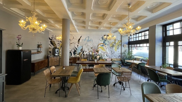 A restaurant with a modern interior, featuring a mix of wooden and upholstered furniture, a large mural on the back wall, and a ceiling with recessed lighting. - Urban Jungle. Hotel Orléans (Orléans)