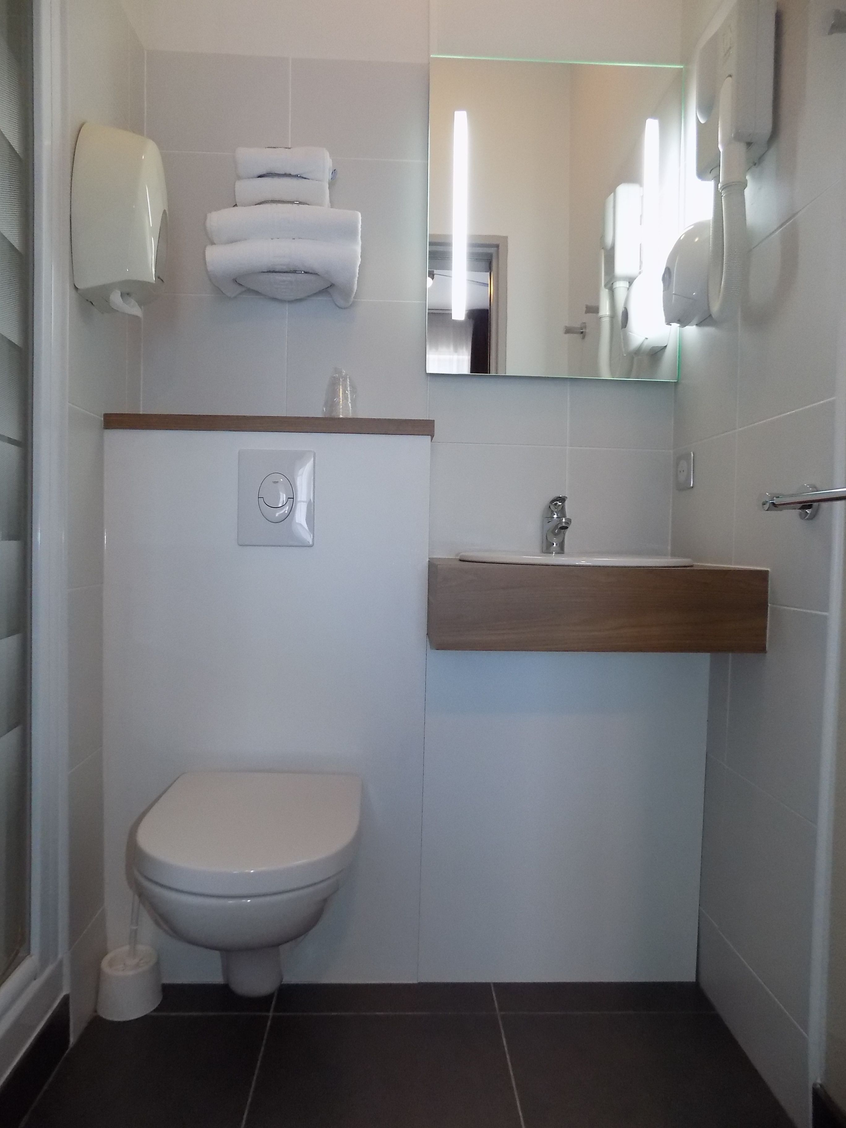 A modern bathroom with a toilet, sink, and towel dispenser.