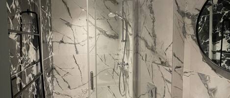 A modern bathroom with a glass-enclosed shower, a toilet, and a black sink.
