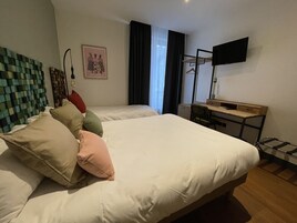 Habitación de hotel con dos camas, un escritorio, una silla, un televisor y una ventana con cortinas.