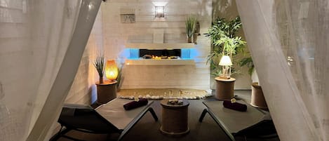 Ein gemütlicher, moderner Essbereich mit Kamin, bequemen Sitzmöglichkeiten und dekorativen Pflanzen.
