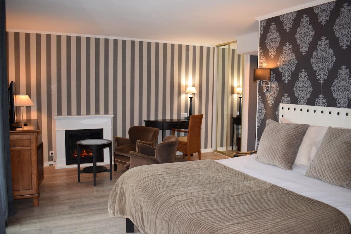 Habitació d'hotel amb un llit gran, una llar de foc, un escriptori i dues cadires.