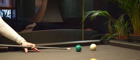 A pool table with a cue stick, billiard balls, and a lamp.