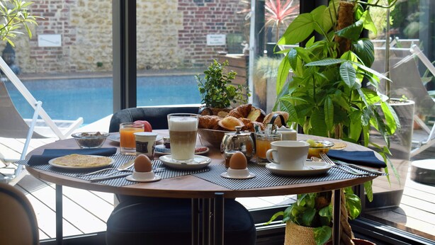 Une table de petit-déjeuner avec des croissants, des œufs et du jus d’orange.