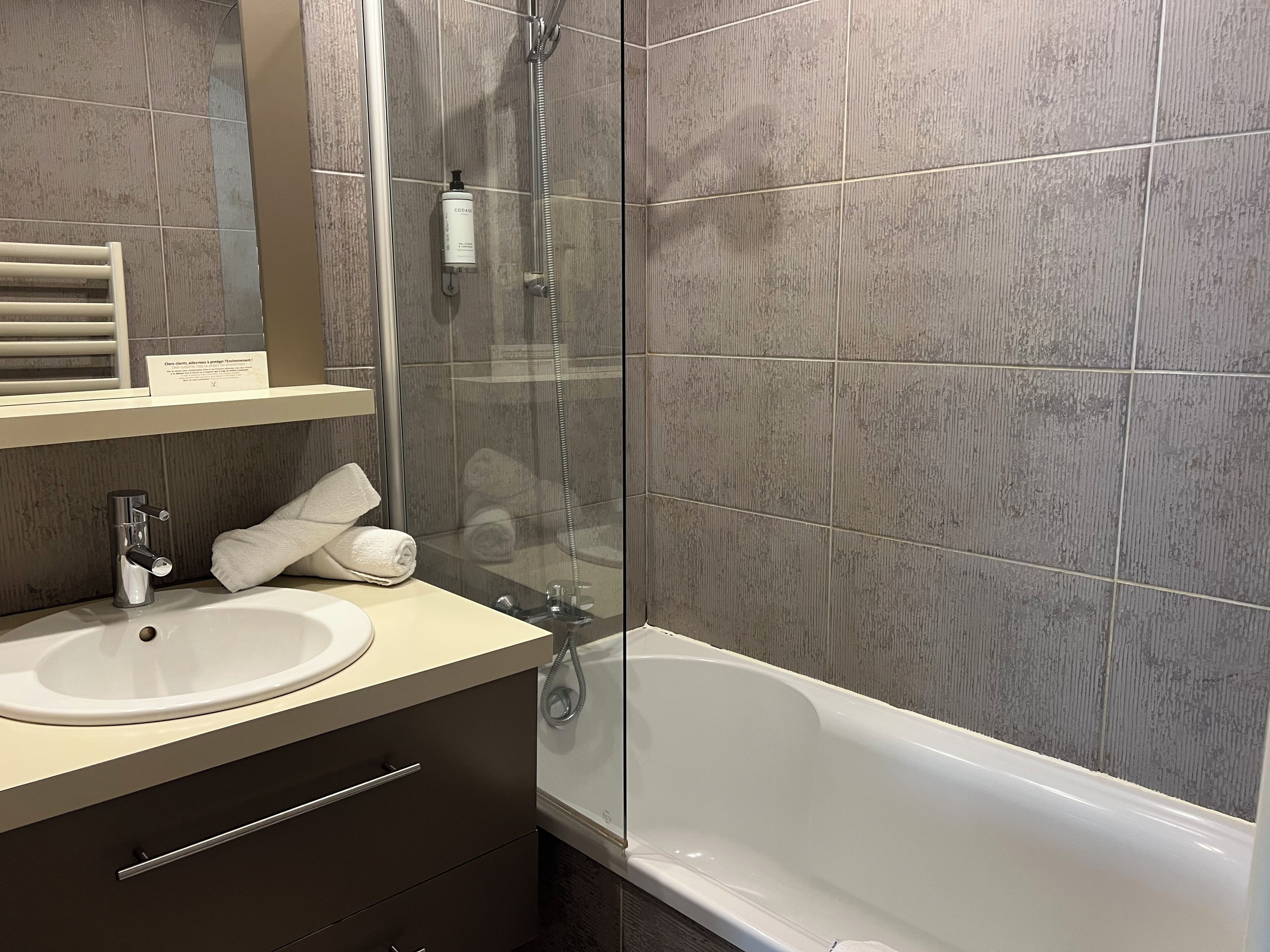 Un baño moderno con ducha de vidrio, lavamanos blanco y bañera.
