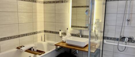 Un baño con bañera, lavabo, espejo y ducha.