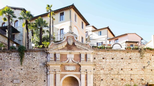 Un mur de pierre surmonté d’une arche décorée et d’une enseigne indiquant « Fonti Cesia ».