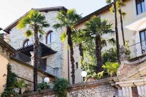 Un edificio in pietra con balconi, palme e un parapetto in ferro battuto.