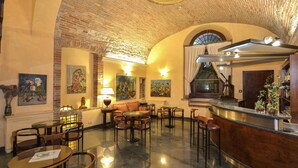 Un hall d’entrée avec un plafond en briques, un comptoir de réception, plusieurs espaces aménagés pour s’asseoir et des œuvres d’art accrochées aux murs.