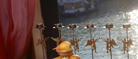 A table with fruit and candles by a window overlooking a canal.