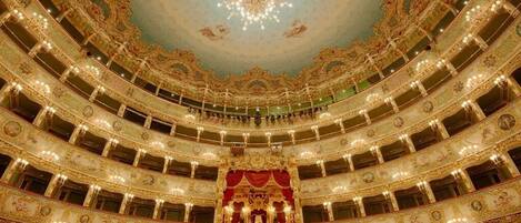 A multi-tiered theater with ornate golden decorations and a central stage.