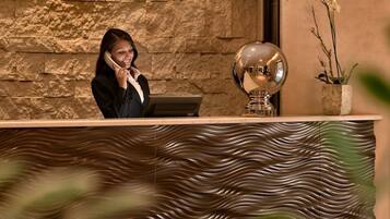 Un'area reception con parete in pietra, una recezionista, una scrivania reception e uno specchio decorativo.