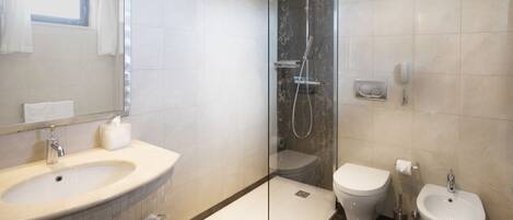 A modern bathroom with a glass-enclosed shower, a sink, a toilet, and a bidet.