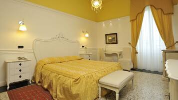 Un dormitorio con cama, mesita de noche, lámpara y una alfombra roja estampada.