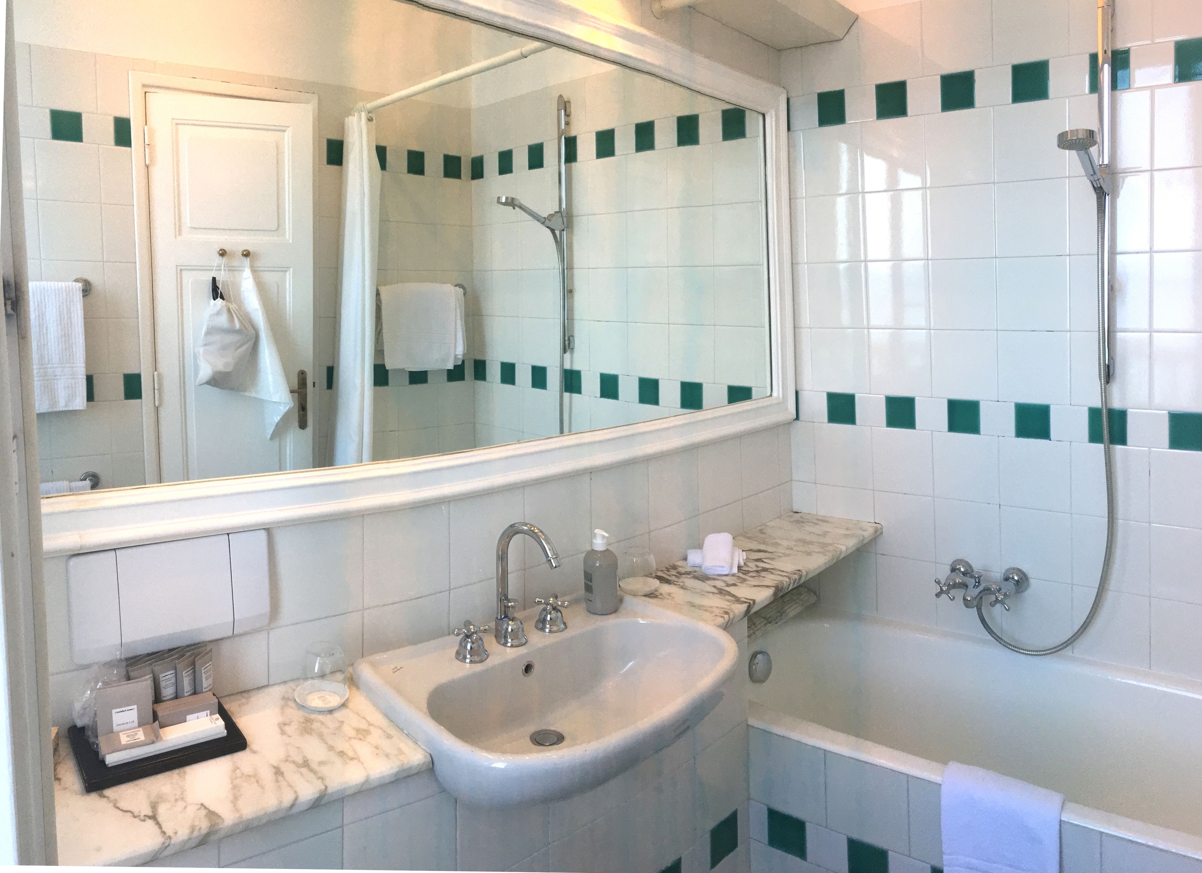 A bathroom with a sink, mirror, shower, and a towel rack.