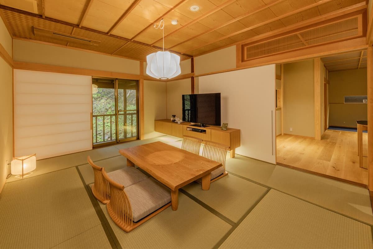 A traditional Japanese room with tatami flooring, a low wooden table, a television, and sliding doors.