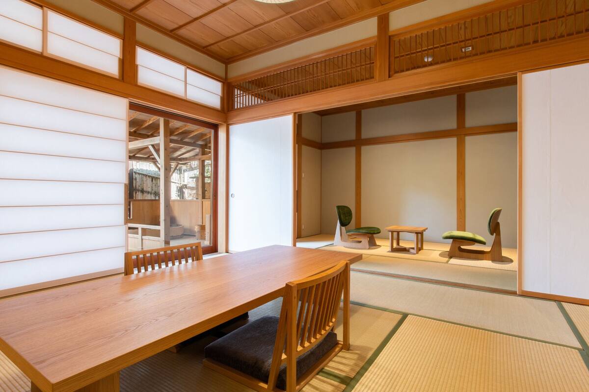 A traditional Japanese room with tatami flooring, a wooden table, and a low wooden desk.
