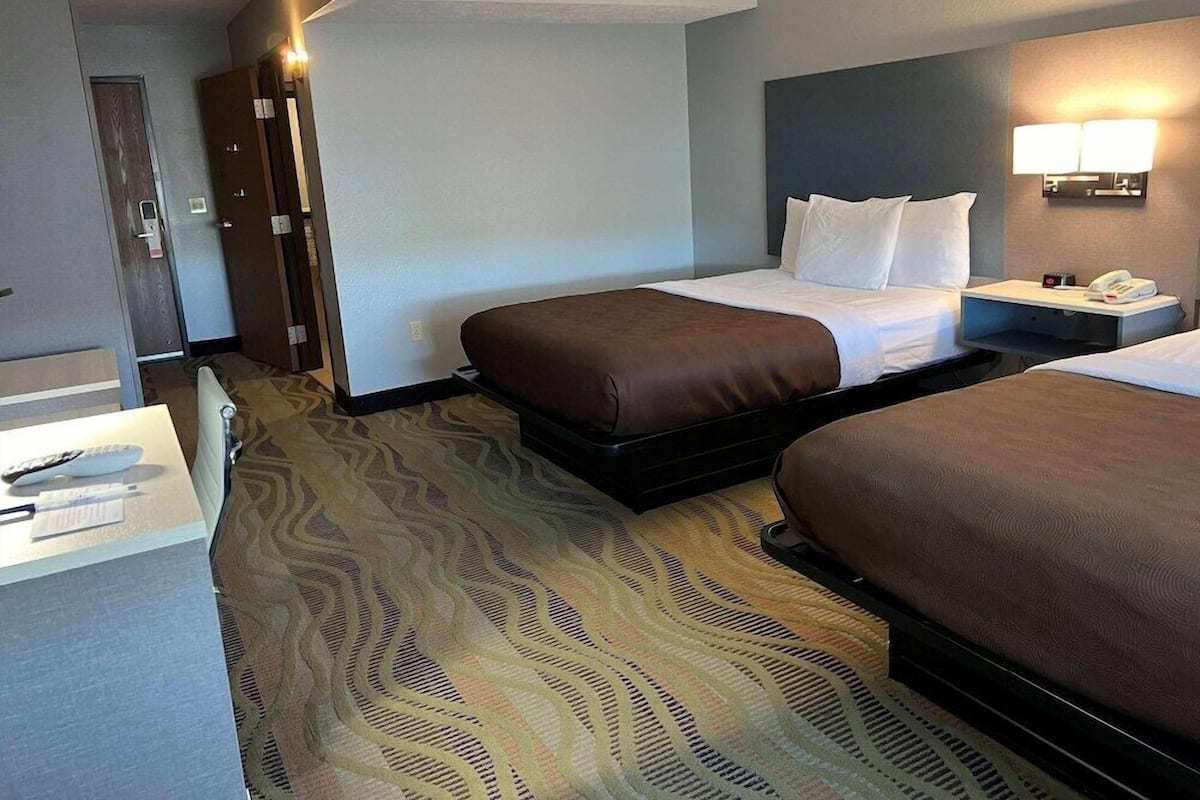 Ein Hotelzimmer mit zwei Betten, einem Schreibtisch und einem Telefon sowie einer Tür.