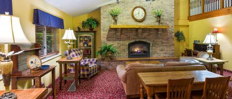 A cozy living room with a fireplace, a ceiling fan, and a red patterned carpet.