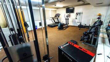 Een sportschool met trainingsapparatuur, een loopband en een halterbank.