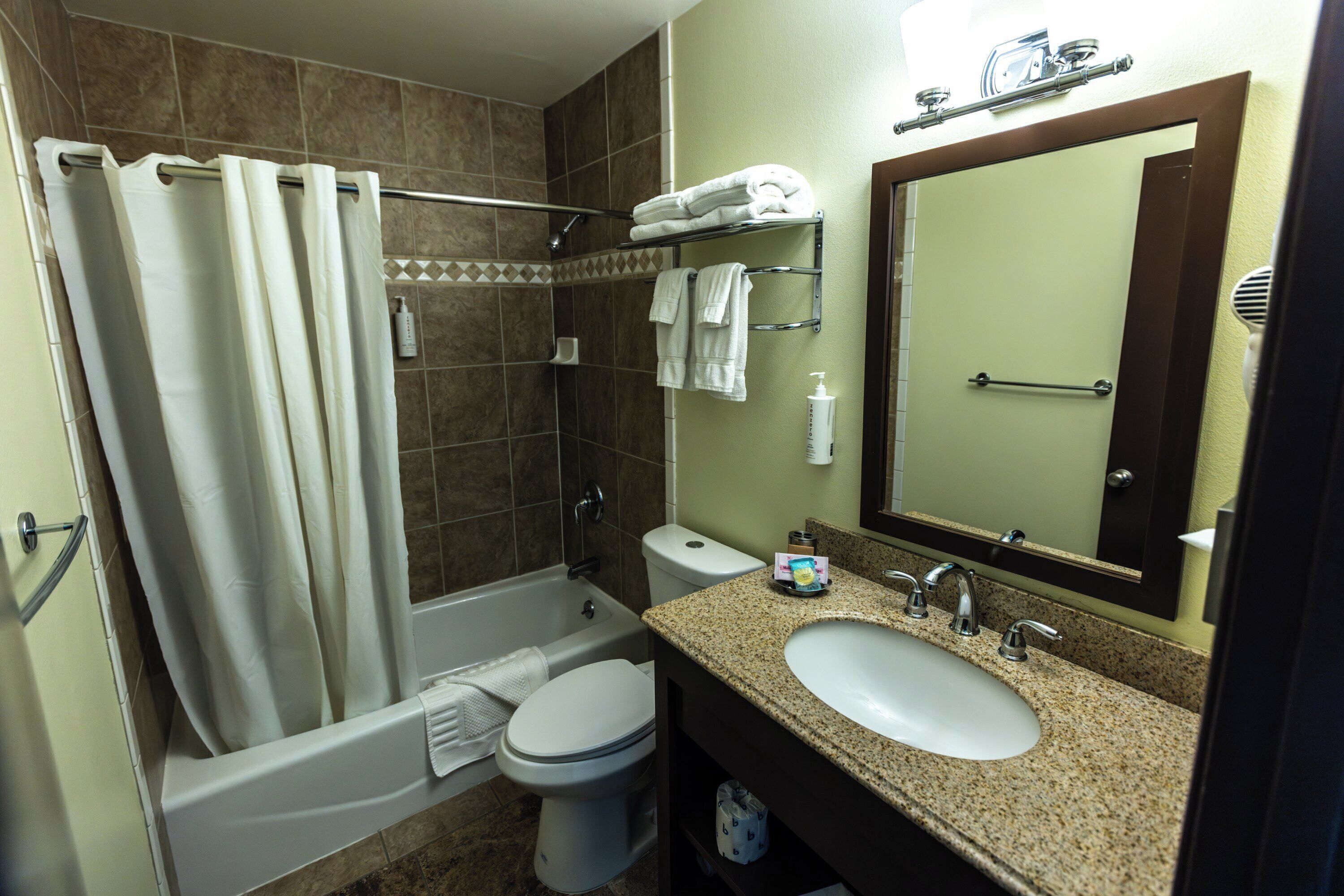 A bathroom with a bathtub, toilet, sink, and a mirror.