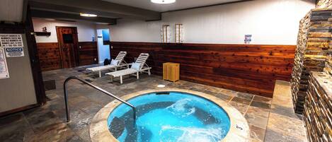 Un jacuzzi con sillones reclinables, una pared de madera y piso de baldosas.