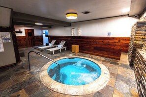 A hot tub with lounge chairs, a wooden wall, and a tiled floor. - The Mammoth Creek Inn (Mammoth Lakes)