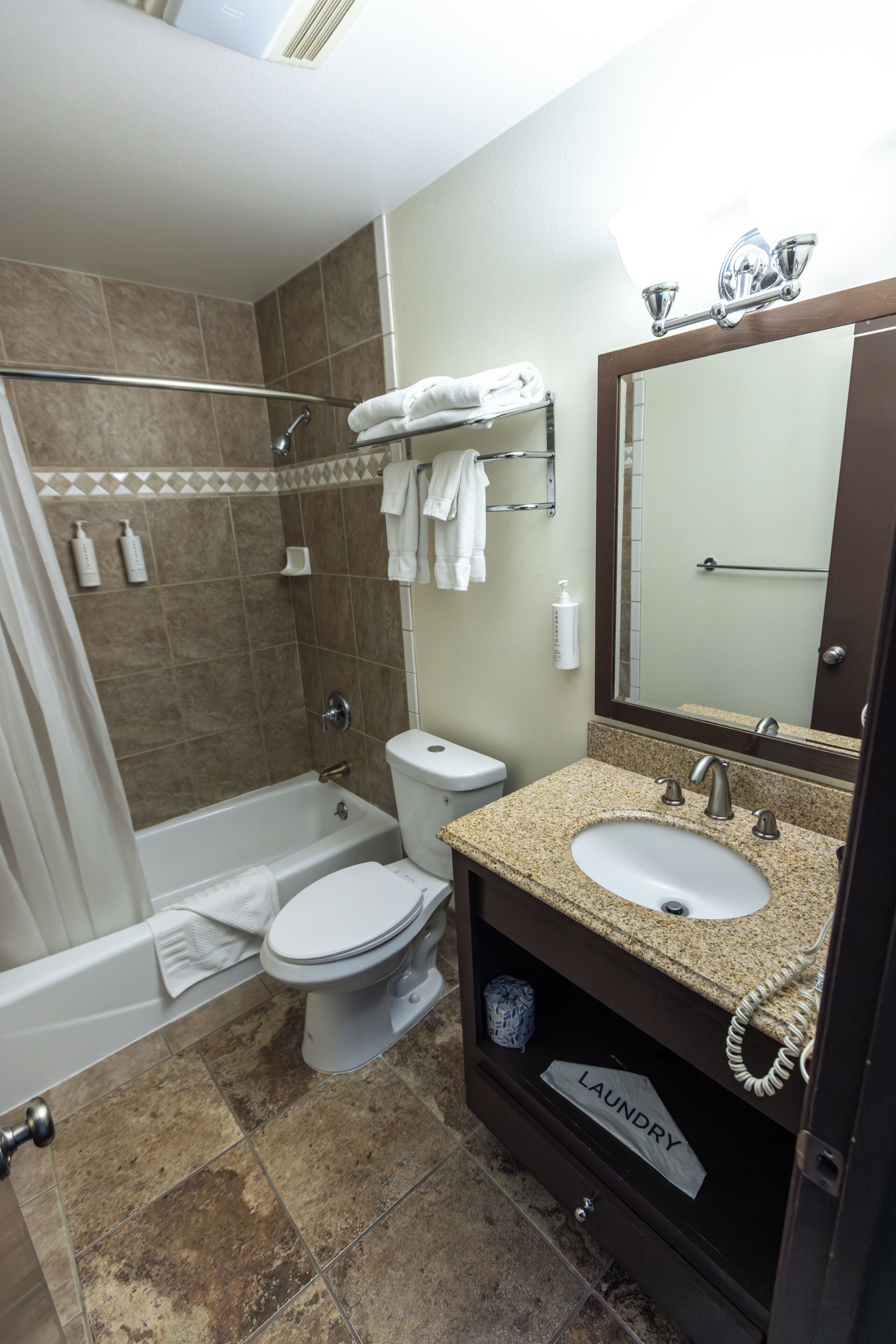 A bathroom with a bathtub, toilet, sink, and a mirror.