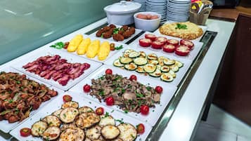 Een ontbijtbuffet met diverse gerechten, zoals spek, eieren en groenten.