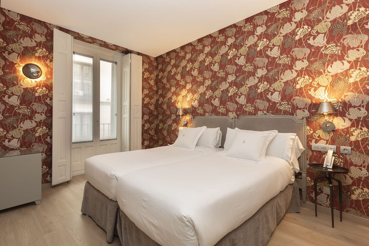 A bedroom with a large bed, two bedside lamps, a nightstand, and a door with a view to the outside.