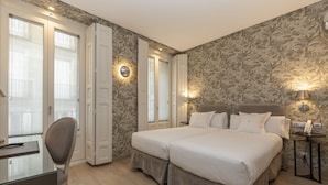 A hotel room with a double bed, a desk with a chair, and a nightstand with a lamp. - Hotel Meninas (Madrid)