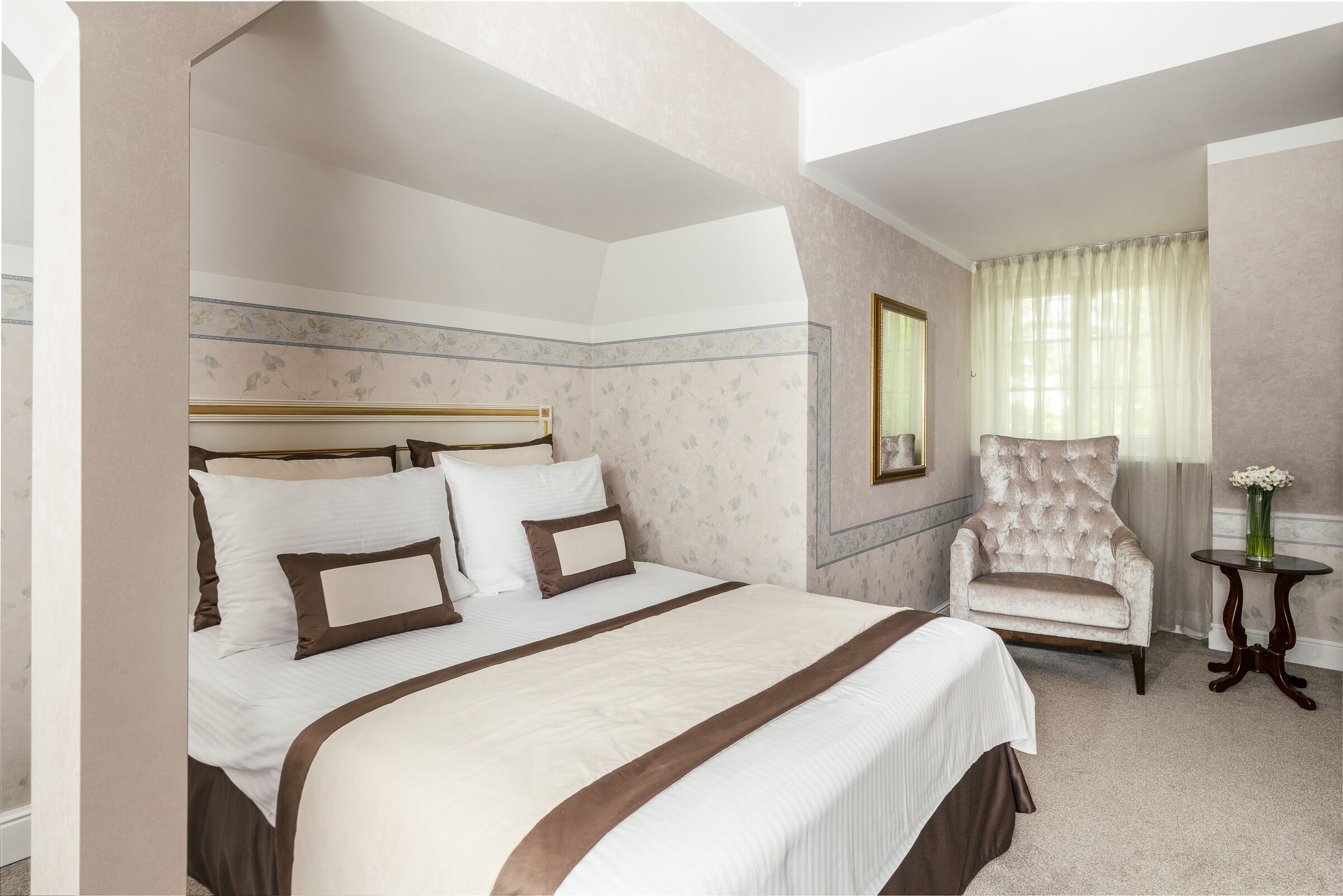 A spacious bedroom with a large bed, a chair, and a small table.