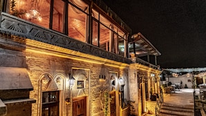 A stone building with large windows, a wooden staircase, and outdoor seating. - Goreme House Hotel (Nevsehir)