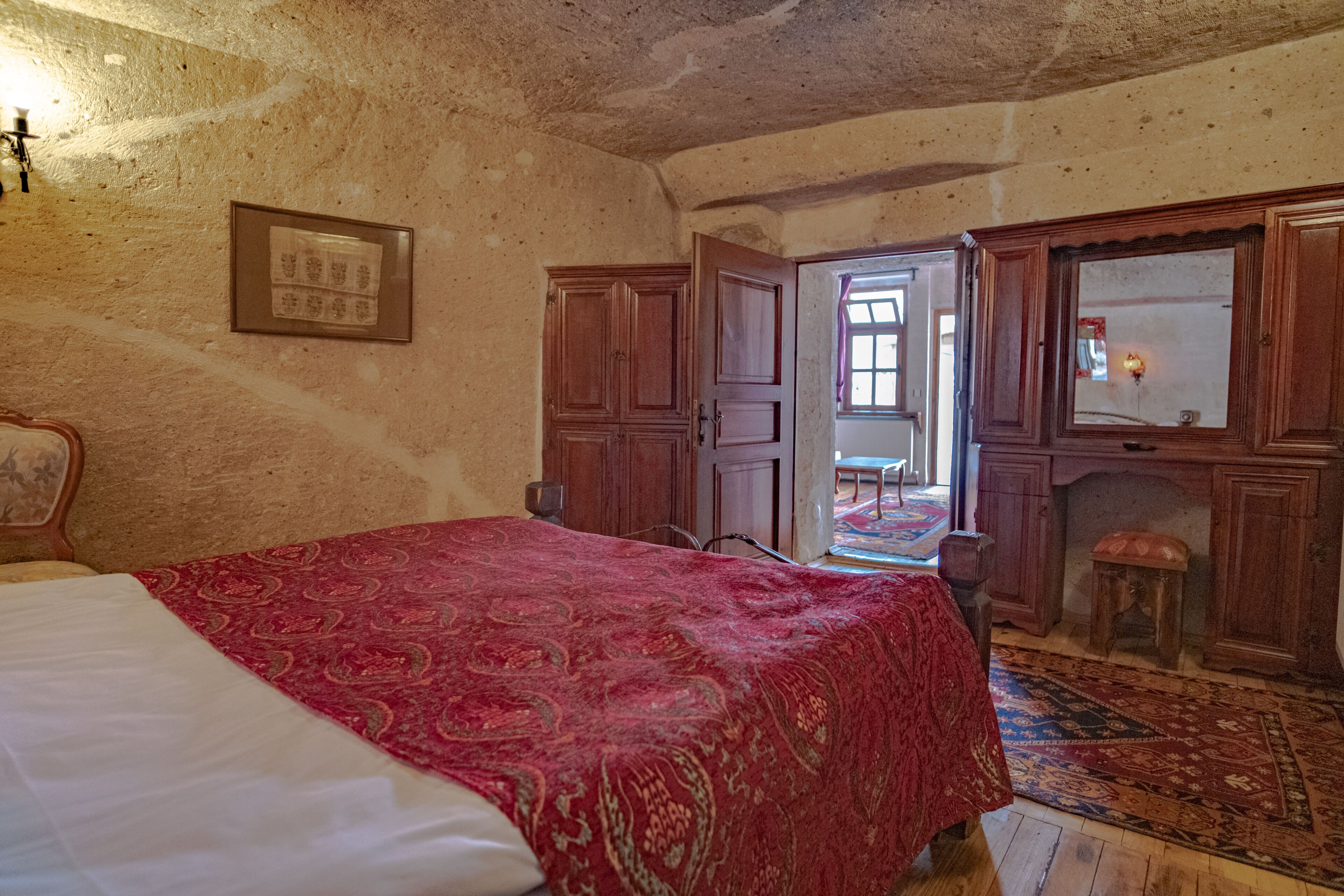 A bedroom with a bed, wooden wardrobe, and a small stool.