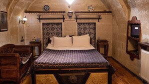 A bedroom with a large bed, wooden furniture, a patterned rug, and an arched ceiling. - Goreme House Hotel (Nevsehir)