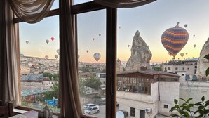A view from a window overlooking a cityscape with hot air balloons, a prominent rock formation, and buildings with satellite dishes. - Goreme House Hotel (Nevsehir)
