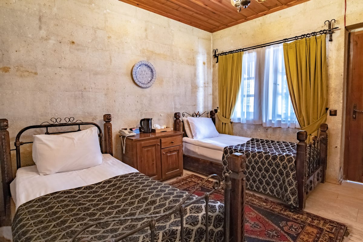 Quarto com duas camas, um aparador de madeira, uma cafeteira e um prato decorativo na parede.