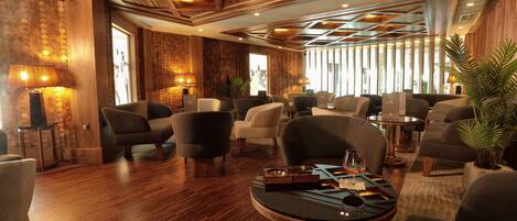 A spacious lounge area with multiple seating options, including sofas and armchairs, arranged around a central coffee table.