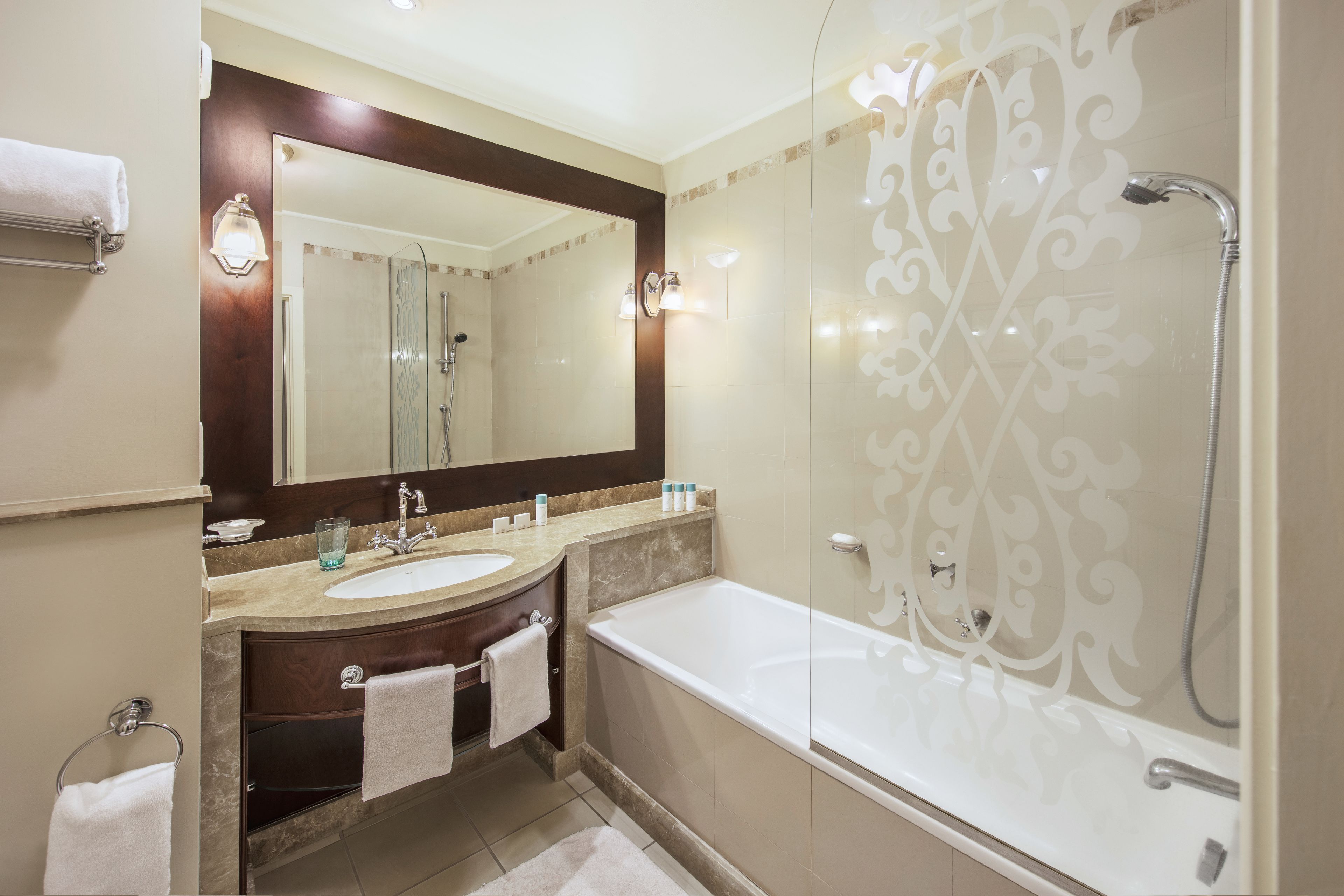 A modern bathroom with a large mirror, a bathtub, and a shower.