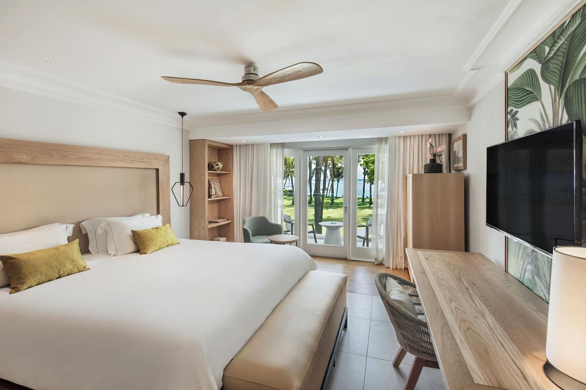 Amplia habitación de hotel con una cama grande, un escritorio, un televisor y vistas al exterior.
