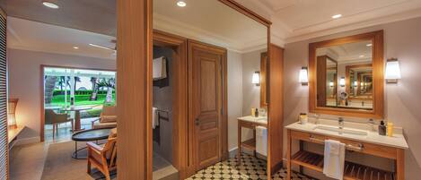 A bathroom with a large mirror, wooden cabinets, a sink, and a shower area.
