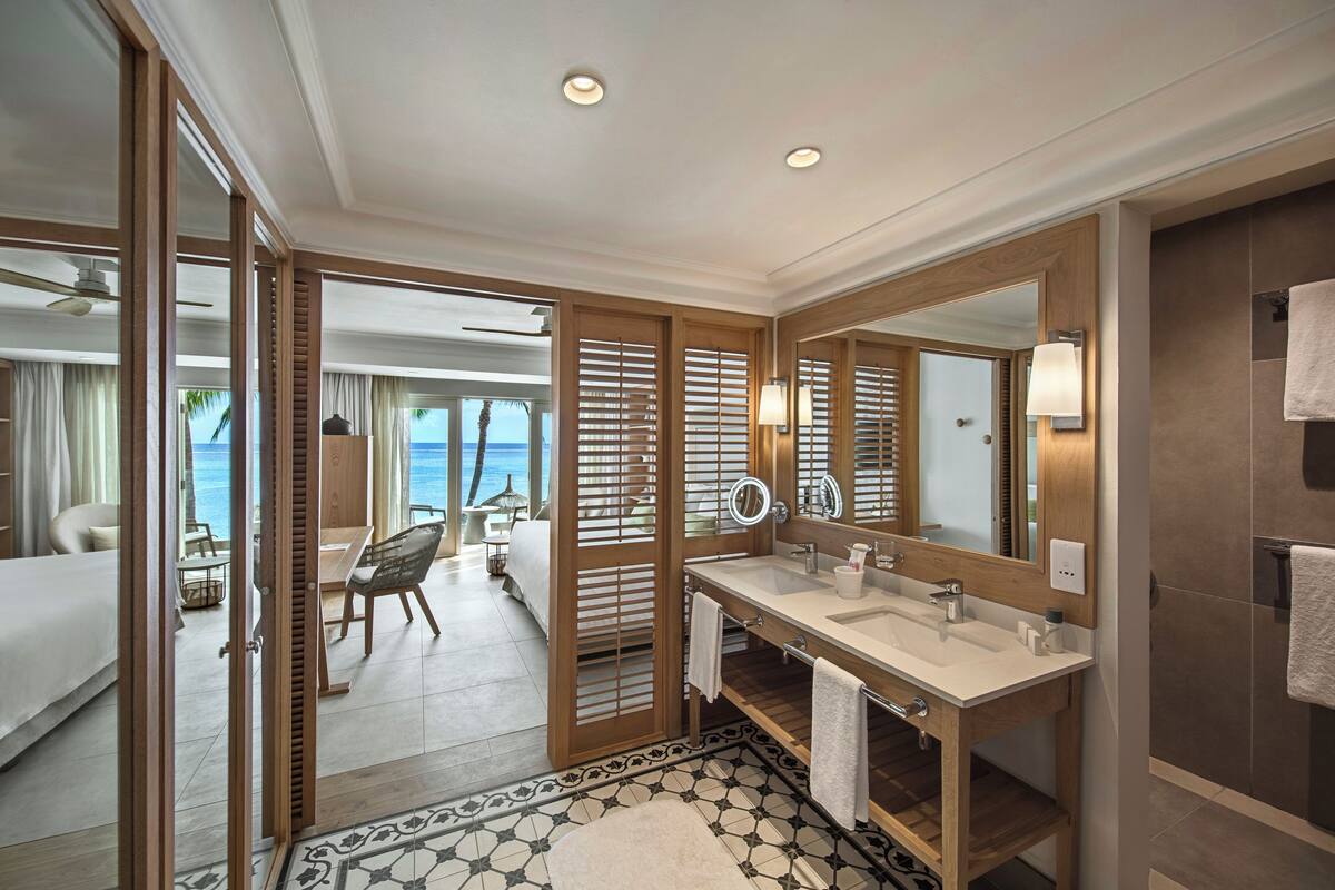 Un baño de hotel moderno con un espejo grande, dos lavamanos y una ducha.