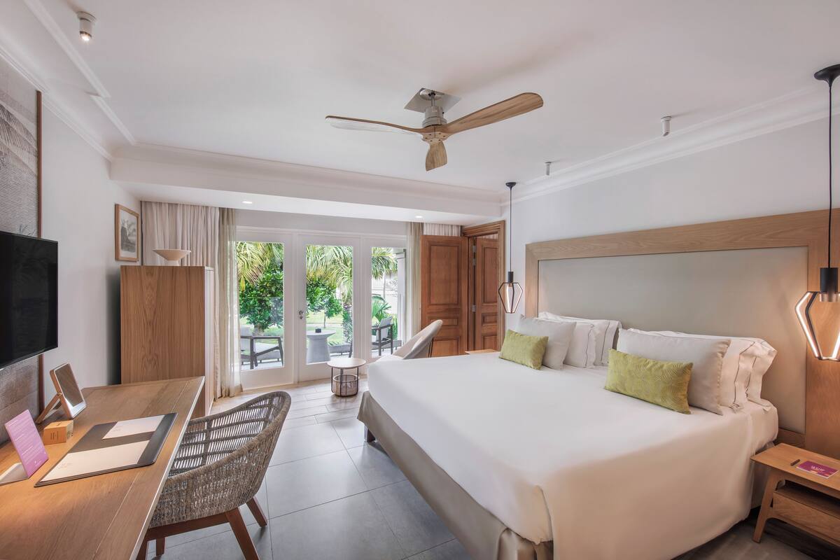 Una habitación de hotel moderna con una cama grande, un escritorio con una computadora, una silla y un televisor.