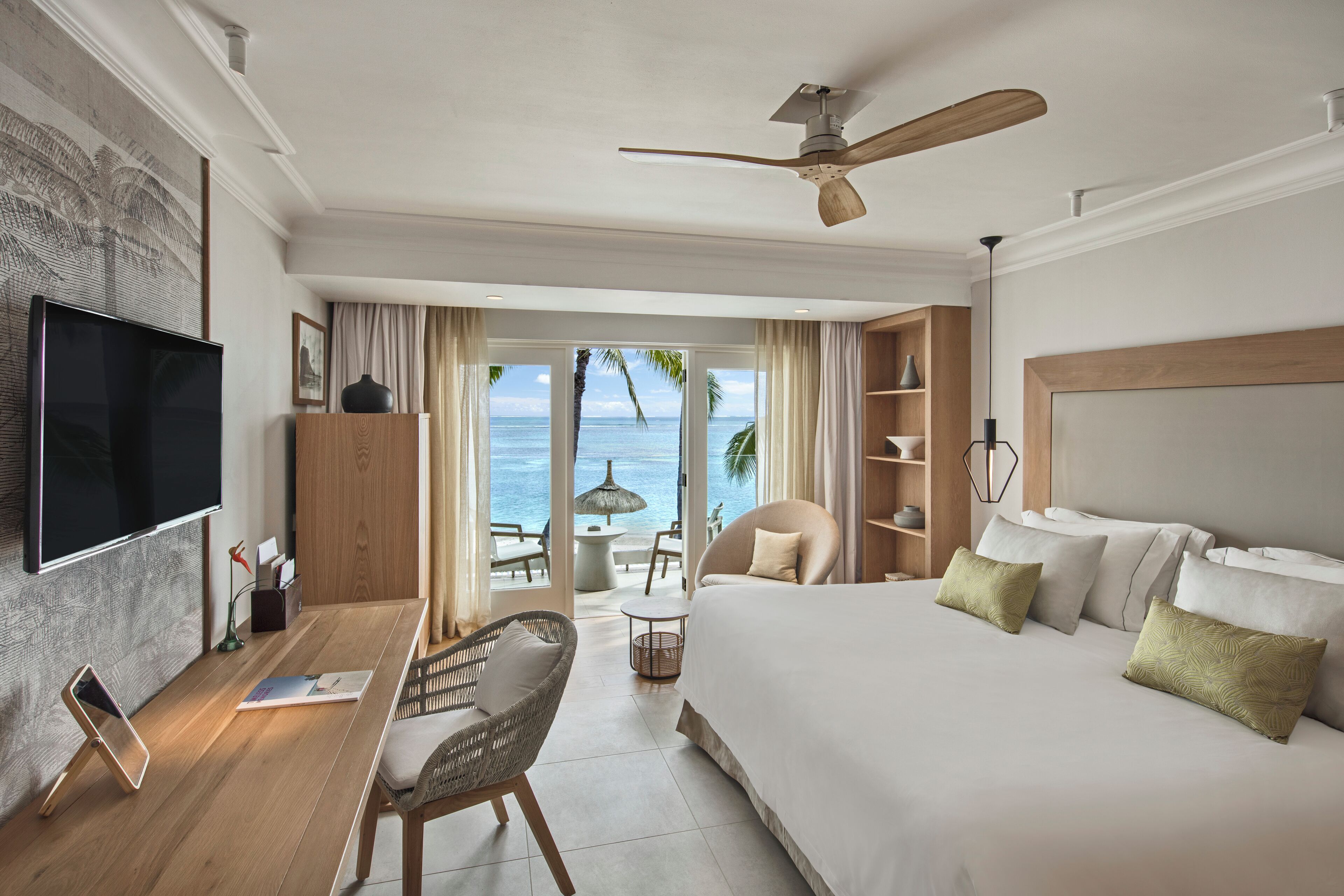 Ein Hotelzimmer mit Bett, Schreibtisch, Computer, Fernseher und Blick auf den Ozean.