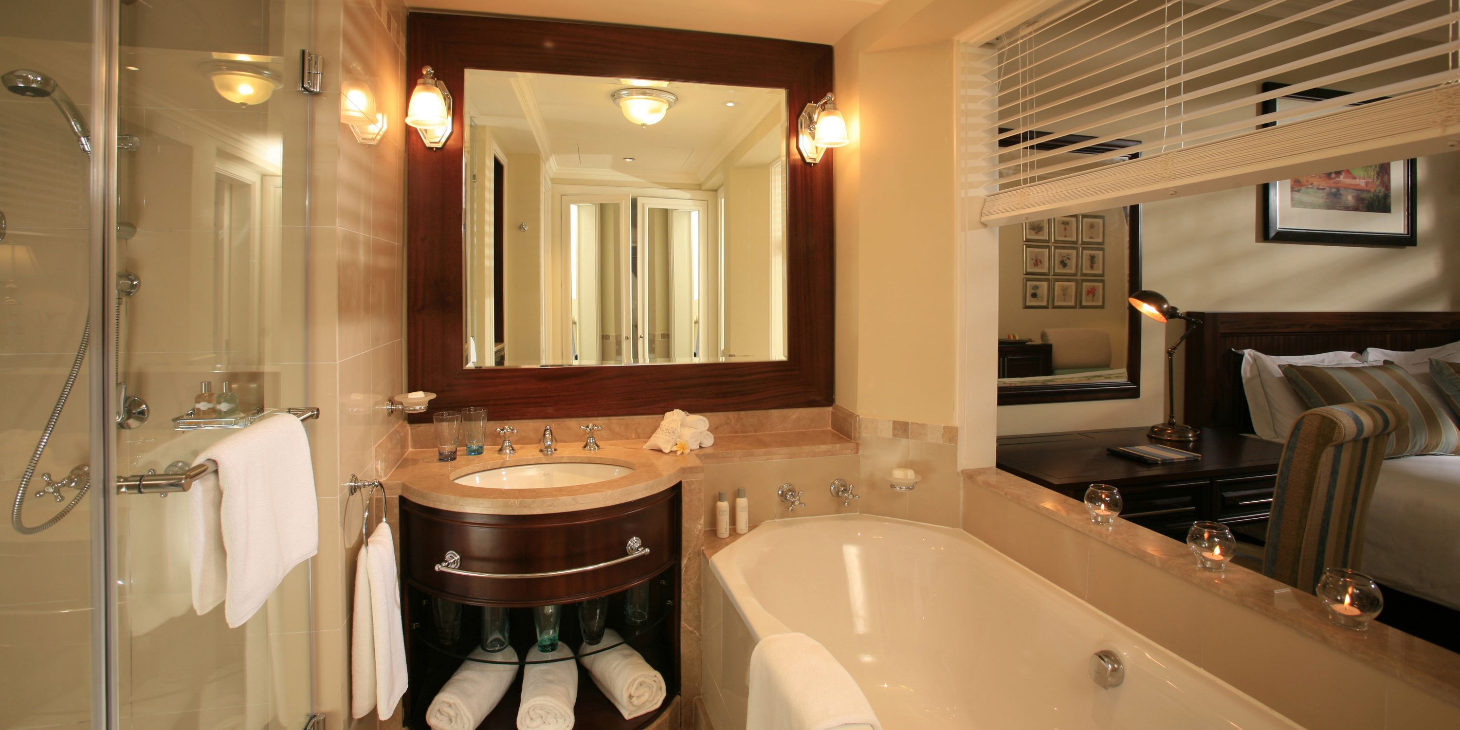 A bathroom with a glass-enclosed shower, a sink with a vanity, a bathtub, and a mirror above the sink.