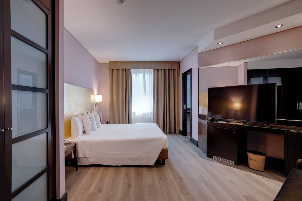 Ein Hotelzimmer mit Bett, Schreibtisch mit Fernseher und Papierkorb.